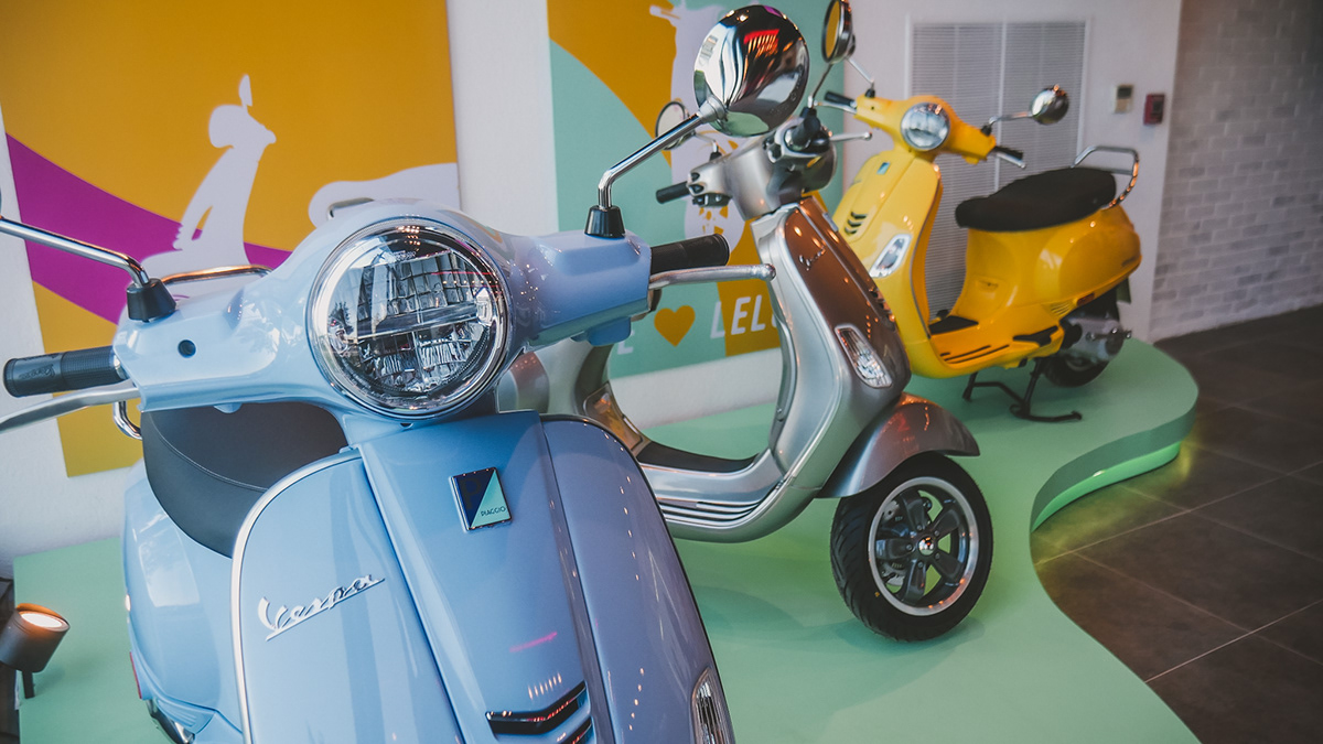 Close-up of Vespa scooters with showroom poster installation